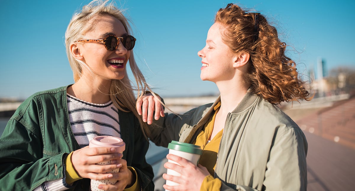 Två unga kvinnor med thermosmuggar.